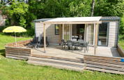 Terrasse des Mobilhome Toulouse bei La Draille in Frankreich, umgeben von Bäumen und Sonnenschein.
