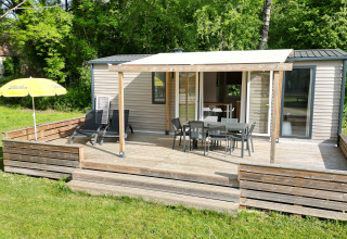 Terraza exterior de Mobilhome Toulouse en La Draille, Francia, rodeada de árboles verdes y luz solar.