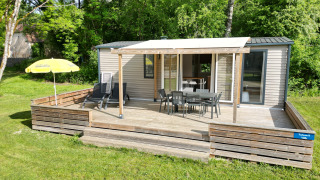 Terrasse des Mobilhome Toulouse bei La Draille in Frankreich, umgeben von Bäumen und Sonnenschein.