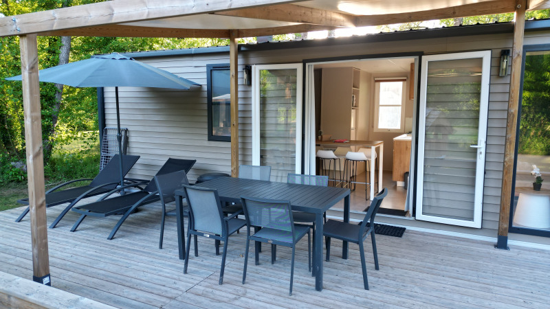 Terraza de madera con comedor exterior y tumbonas en Mobilhome Toulouse, La Draille, Francia.