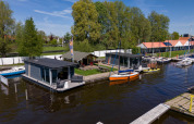 Floating cabins and sailboats at Marina Heeg with Safari tent Heeg in a scenic natural setting, Netherlands.