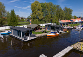 Cabañas flotantes y veleros en Marina Heeg con la tienda Safari tent Heeg en un entorno natural, Países Bajos.