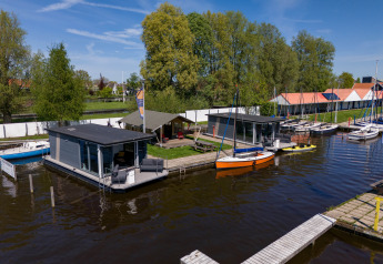 Floating cabins and sailboats at Marina Heeg with Safari tent Heeg in a scenic natural setting, Netherlands.
