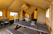Binnenkant van een safaritent bij Marina Heeg in Nederland, met houten tafel en keukenhoek.