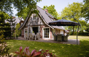 Foto de Wellness Lodge XL en Hof van Salland, Países Bajos, con patio, muebles y jardín verde alrededor.