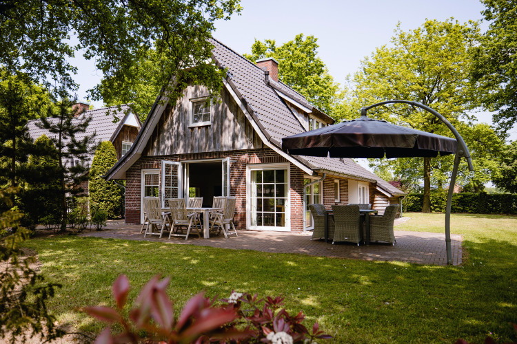 Foto de Wellness Lodge XL en Hof van Salland, Países Bajos, con patio, muebles y jardín verde alrededor.