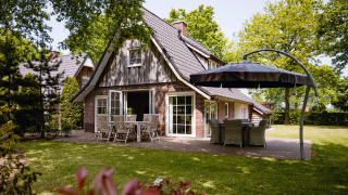 Wellness Lodge XL am Hof van Salland in den Niederlanden mit Terrasse, Gartenmöbeln und grünem Garten.