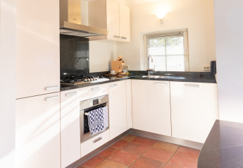 Moderne keuken in Wellness Lodge XL bij Hof van Salland met witte kasten, oven en groot raam.