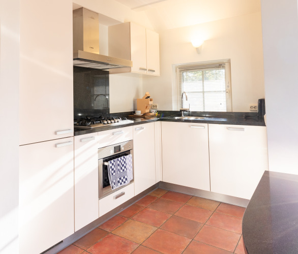 Moderne keuken in Wellness Lodge XL bij Hof van Salland met witte kasten, oven en groot raam.