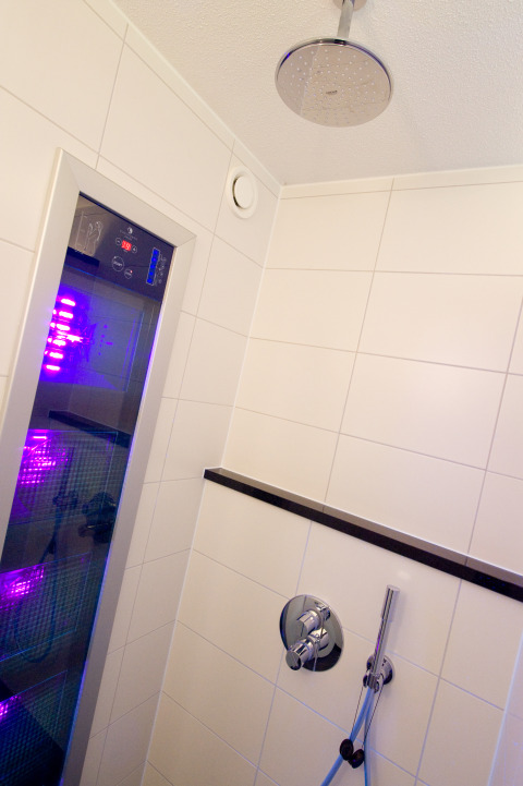 Doccia moderna con soffione a pioggia, pannello di controllo e luce LED viola in Wellness Lodge XL, Hof van Salland, Paesi Bassi.