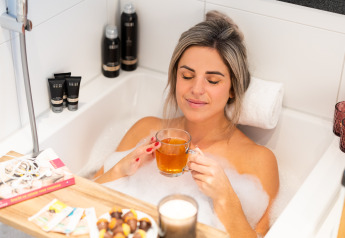 Mujer relajándose en una bañera con burbujas, té, snacks y libros en Wellness Lodge XL, Hof van Salland, Países Bajos.