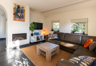 Soggiorno moderno nella Wellness Lodge XL, Hof van Salland, Paesi Bassi, con divano, camino e decorazioni.