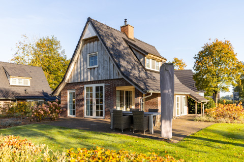 Wellness Lodge XL en Hof van Salland en Países Bajos, casa pequeña con terraza y vegetación en otoño.