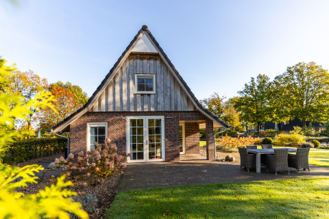 Tiny house Wellness Lodge XL in Hof van Salland in Nederland, omgeven door tuin en buitentafel.