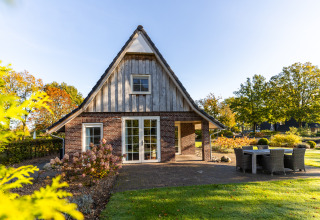 Pequeña casa Wellness Lodge XL en Hof van Salland, Países Bajos, rodeada de jardín y muebles de exterior.