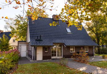 Et hyggeligt Wellness Lodge XL tiny house i Hof van Salland, Holland, omgivet af farverige efterårstræer.
