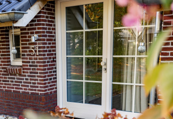 Voordeur van Wellness Lodge XL in Hof van Salland, Nederland, met glazen deuren en bakstenen gevel.