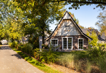 Wellness Lodge XL à Hof van Salland, une petite maison aux Pays-Bas entourée d'arbres et de verdure.