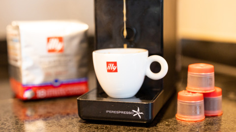 Máquina de café illy preparando café en Wellness Lodge XL, Hof van Salland, con cápsulas y bolsa.
