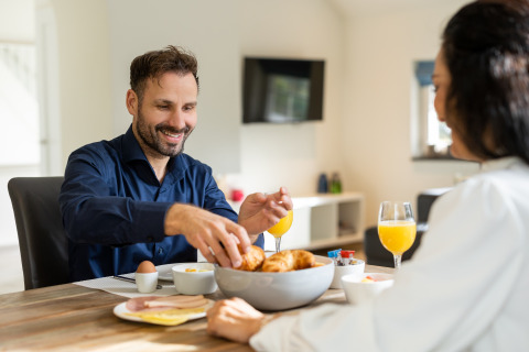 Man and woman enjoying breakfast with croissants and juice at Wellness Lodge XL, Hof van Salland, Netherlands.