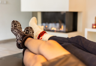 Dos personas se relajan con calcetines cómodos junto a la chimenea en Wellness Lodge XL, Hof van Salland, Países Bajos.