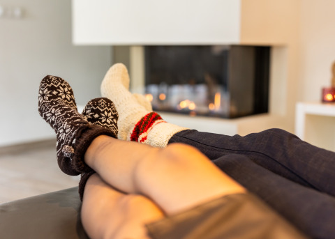 Two people relaxing in cozy socks by the fireplace in Wellness Lodge XL, Hof van Salland, Netherlands.