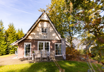 Wellness Lodge XL aan Hof van Salland in Nederland, buitenkant met terrastafel in groene, bosrijke tuin.