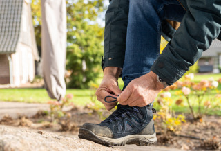 Una persona se ata las botas de senderismo frente a la Wellness Lodge XL en Hof van Salland, Países Bajos.