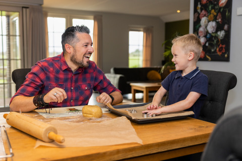 Father and son baking cookies together at a table in Wellness Lodge XL at Hof van Salland, Netherlands.