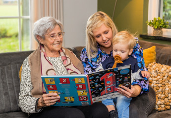 Tres generaciones leen juntas en una acogedora sala de Wellness Lodge XL en Hof van Salland, Países Bajos.