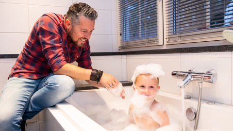 Padre jugando con su hijo en una bañera con burbujas en Wellness Lodge XL, Hof van Salland, Países Bajos.