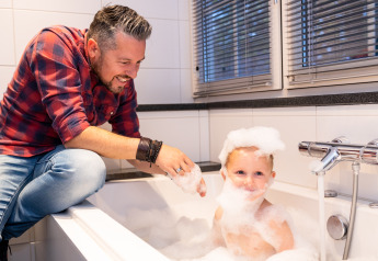 Padre jugando con su hijo en una bañera con burbujas en Wellness Lodge XL, Hof van Salland, Países Bajos.