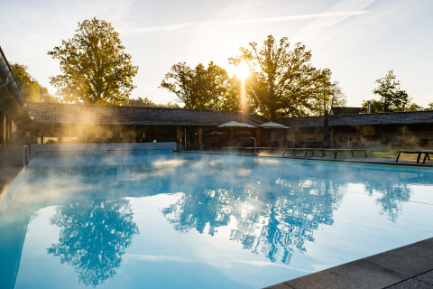 Outdoor swimming pool at Wellness Lodge XL, Hof van Salland in the Netherlands, steaming in morning sun.