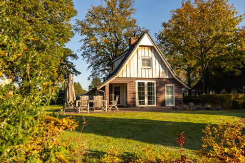 Sunny view of Wellness Lodge XL at Hof van Salland, Netherlands, surrounded by garden and trees.