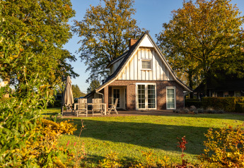 Vue ensoleillée de Wellness Lodge XL à Hof van Salland, Pays-Bas, entouré de jardin et d’arbres.