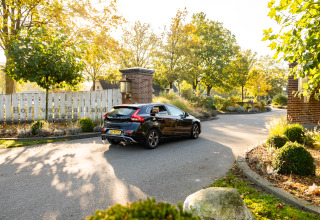 Coche negro en la entrada de Wellness Lodge XL en Hof van Salland, rodeado de árboles y jardines en Holanda.