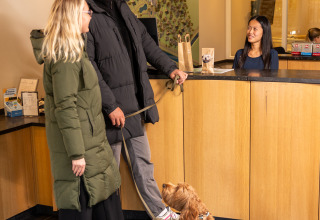 Pareja con perro realizando el check-in en la recepción de Wellness Lodge XL, Hof van Salland, Países Bajos.