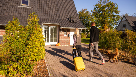 Una pareja llega con su perro y una maleta a Wellness Lodge XL en Hof van Salland, Países Bajos.