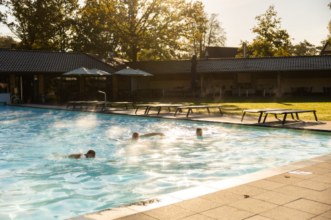 Piscina all'aperto con persone che nuotano e lettini al Wellness Lodge XL, Hof van Salland, Paesi Bassi.