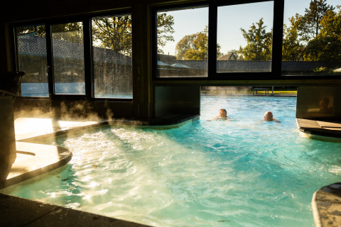 Piscina interna-esterna con vapore, due persone nuotano, Wellness Lodge XL a Hof van Salland, Paesi Bassi.