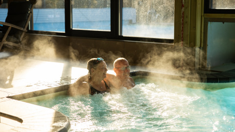 Dos personas se relajan en un jacuzzi humeante en Wellness Lodge XL en Hof van Salland, Países Bajos.