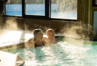 Two people relaxing in a steaming hot tub at Wellness Lodge XL at Hof van Salland in the Netherlands.