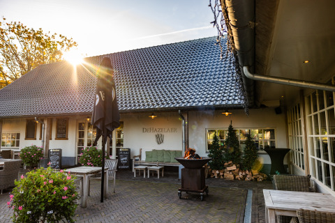 Terraza exterior de la Wellness Lodge XL en Hof van Salland, Países Bajos, con asientos cómodos y puesta de sol.