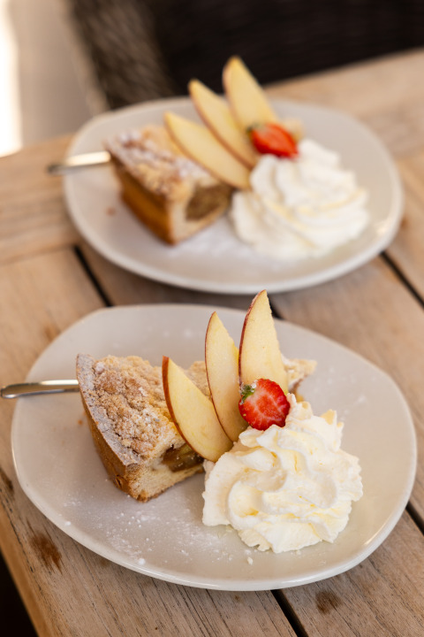 Two plates with apple pie, whipped cream, apple slices and strawberry, served in Wellness Lodge XL, Netherlands.
