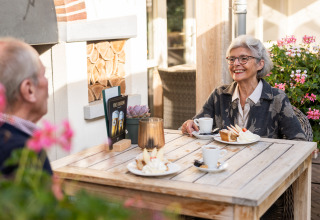 Coppia anziana gusta caffè e torta all'aperto presso Wellness Lodge XL a Hof van Salland, Paesi Bassi.