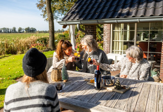 Cuatro mujeres disfrutan de bebidas en la terraza de la Wellness Lodge XL, tiny house en Hof van Salland, Países Bajos.