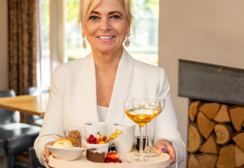 Mujer con chaqueta blanca sirviendo postres y bebida en Wellness Lodge XL, Hof van Salland, Países Bajos.