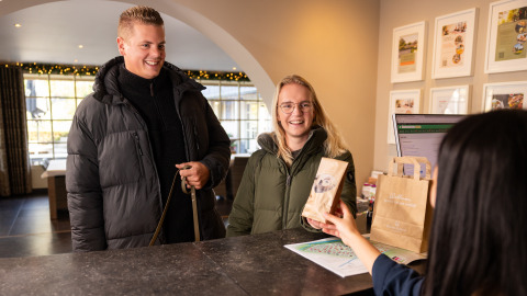 Due ospiti fanno il check-in alla reception di Wellness Lodge XL presso Hof van Salland, Paesi Bassi, e ricevono un regalo.