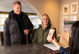 Dos huéspedes se registran en la recepción de Wellness Lodge XL en Hof van Salland, Países Bajos, y reciben un obsequio.