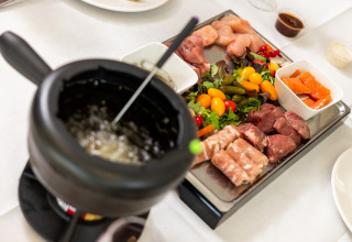 Bandeja de fondue con carne cruda, verduras y salsas en Wellness Lodge XL, Hof van Salland, Países Bajos.